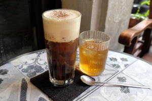 Glass of ca phe muoi salt coffee with salted cream foam over dark iced coffee in Hue