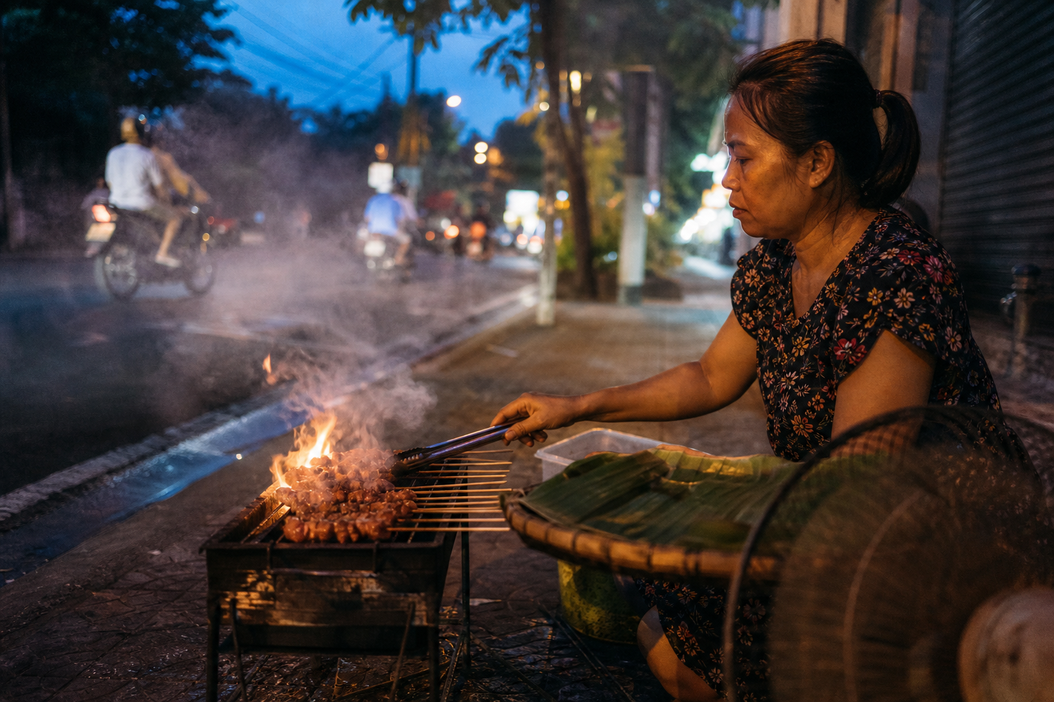 Vietnamese street vendor grilling pork skewers over glowing charcoal on the pavement at dusk with smoke rising