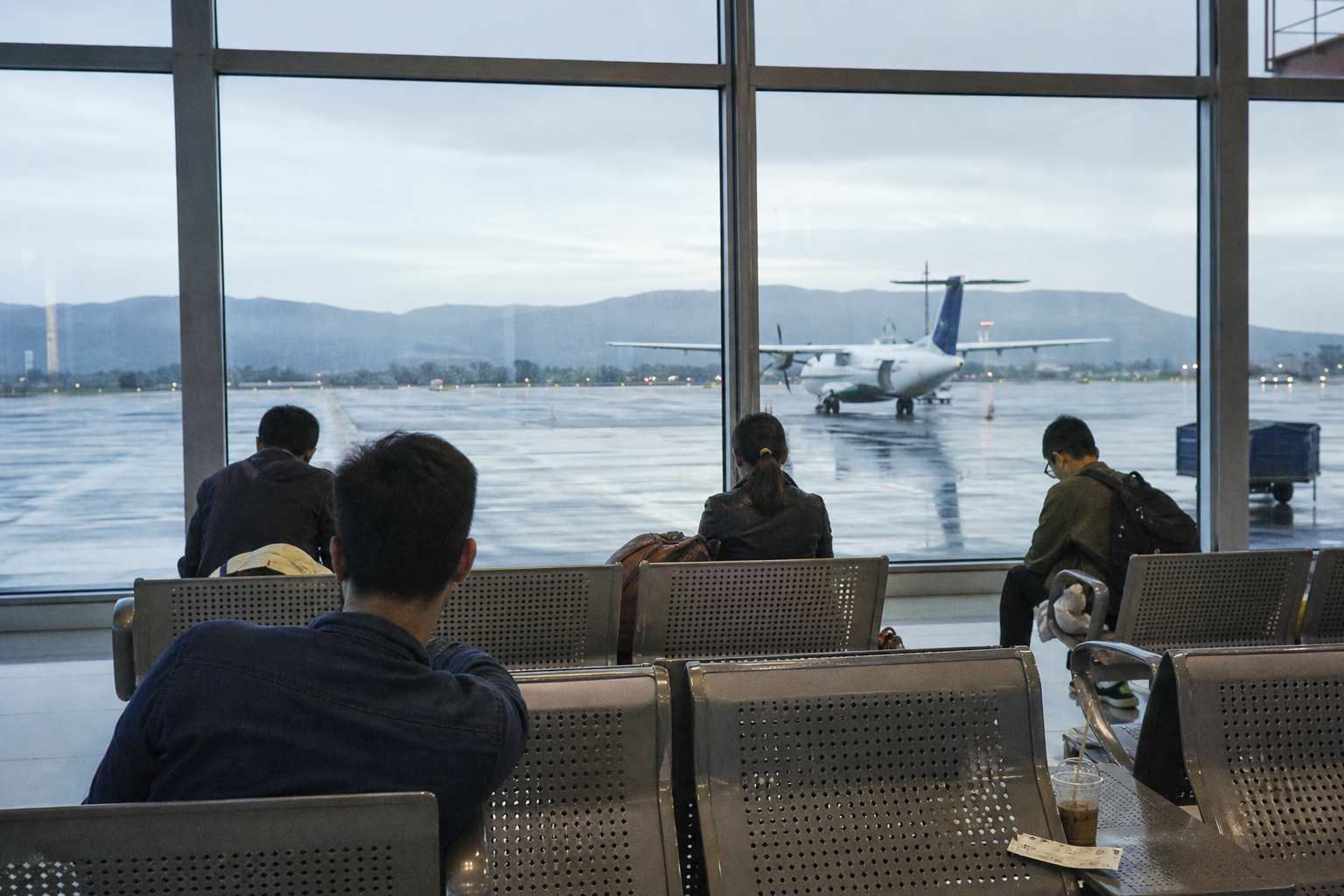 Vietnam domestic airport departure area at dawn with travelers waiting near the windows