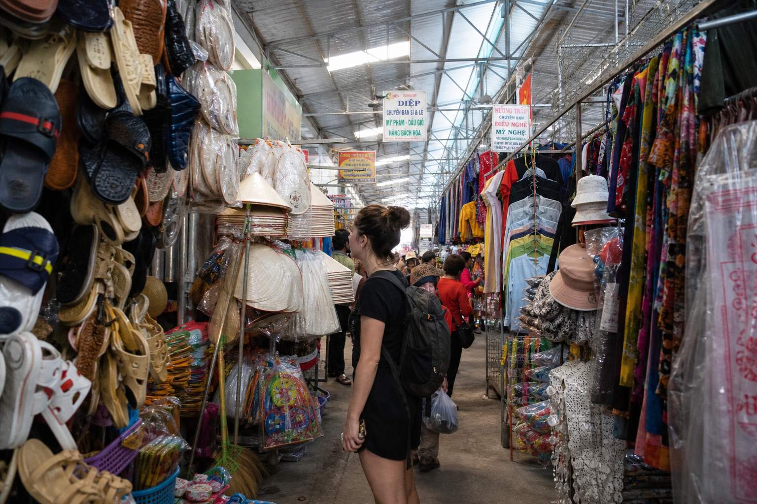 Local Vietnamese market aisle selling plastic sandals, conical hats and cheap clothing to a browsing traveler