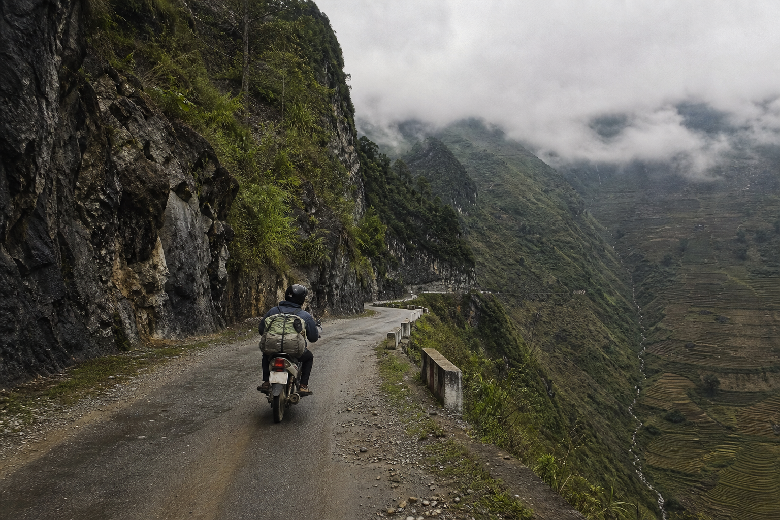Motorbike rider on a winding mountain road in northern Vietnam with limestone cliffs and mist