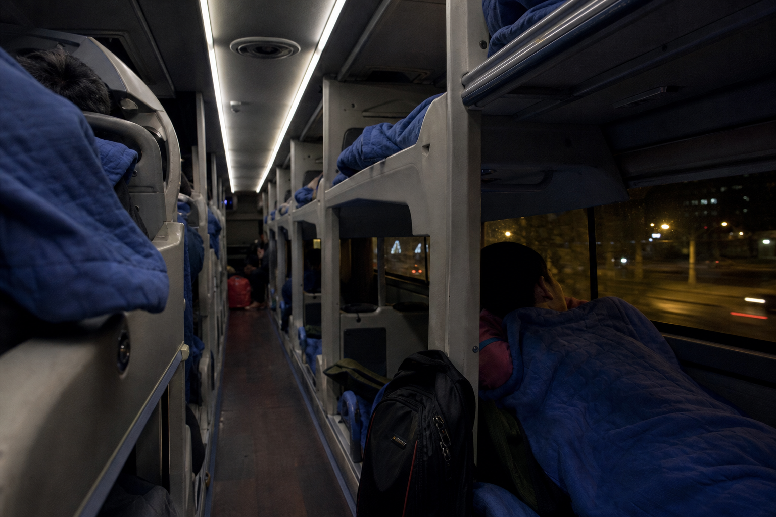Interior of a Vietnamese overnight sleeper bus with two tiers of reclining berths and blue blankets
