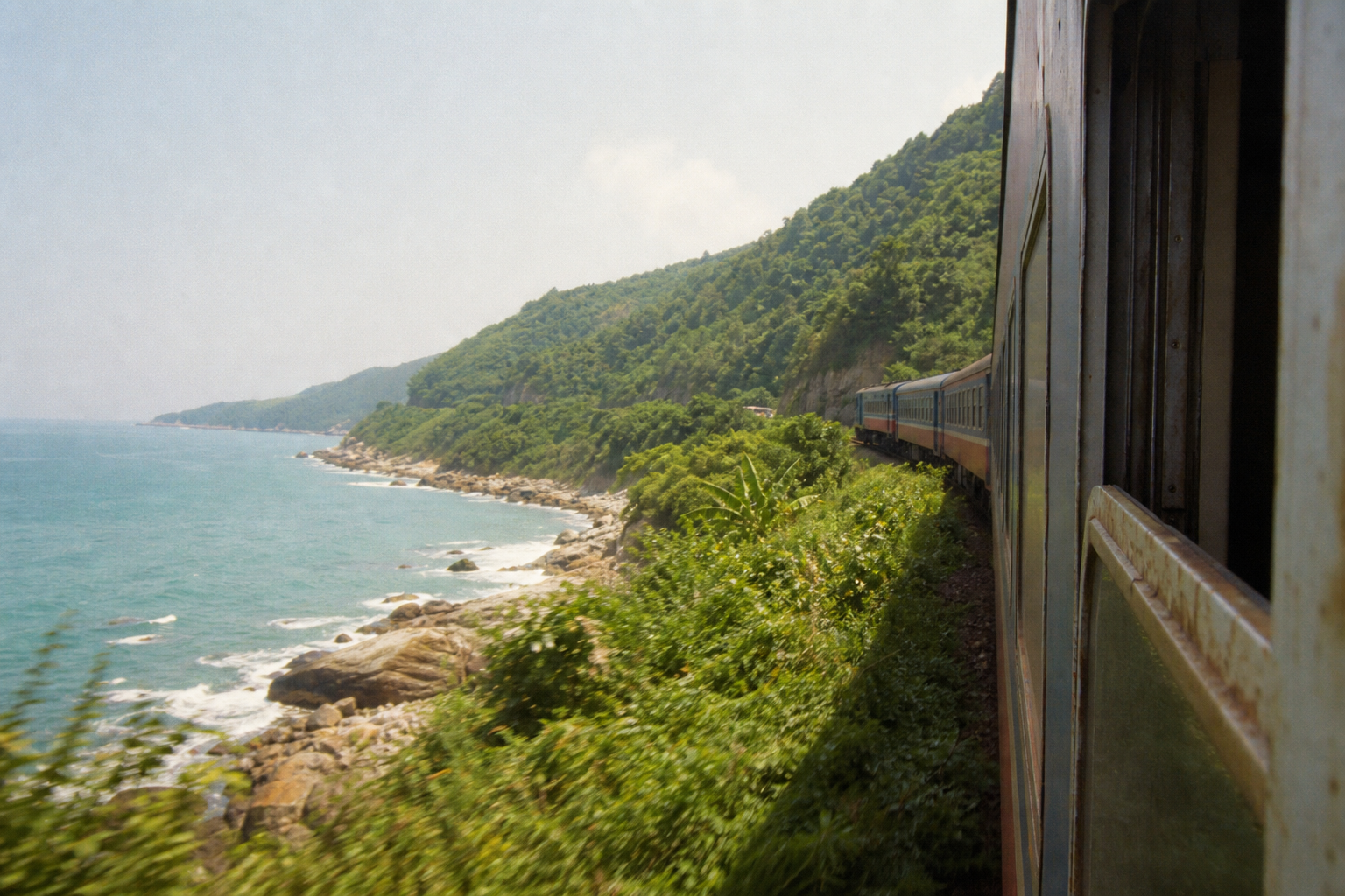 Vietnam train curving along a coastal cliff near the Hai Van Pass