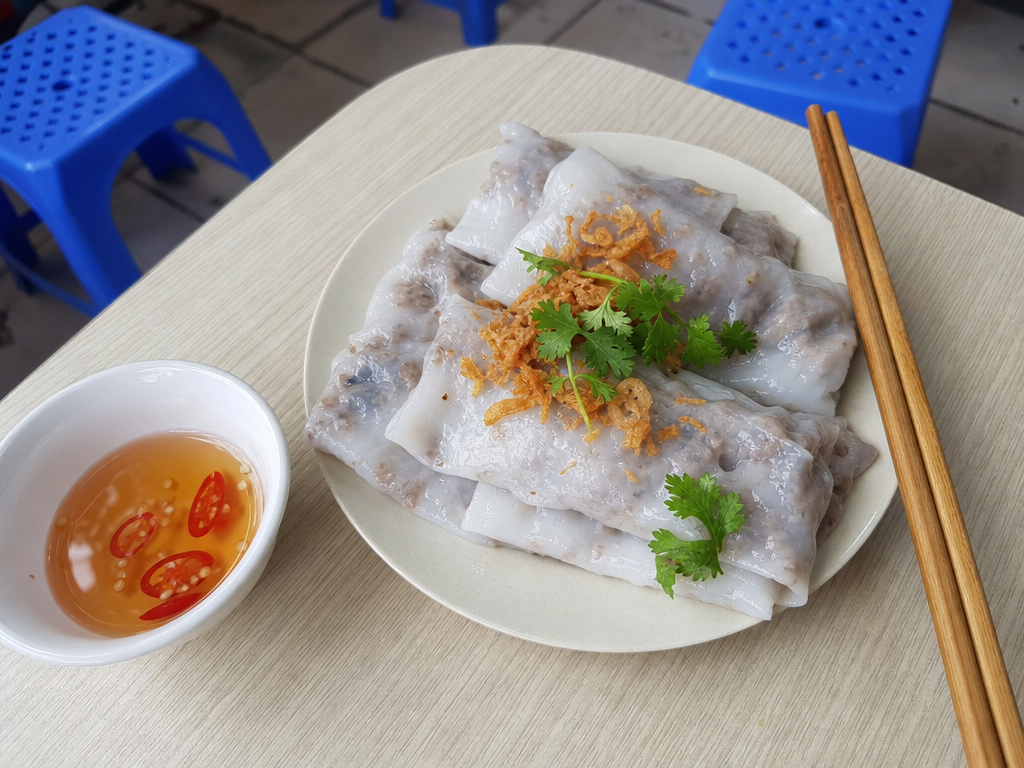 A plate of steamed bánh cuốn rolls with fried shallots and dipping sauce